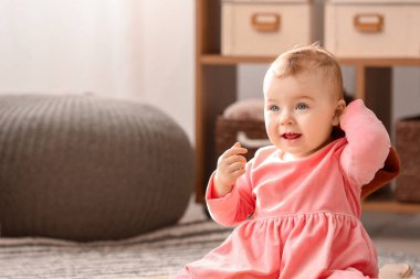 Evde şık giyinmiş şirin bir kız bebek.