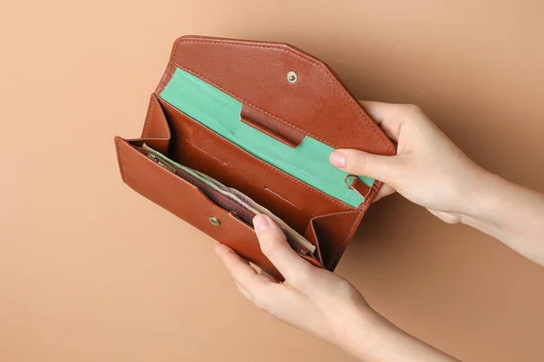 Frauenhände mit Portemonnaie und Geld auf farbigem Hintergrund — Stockfoto