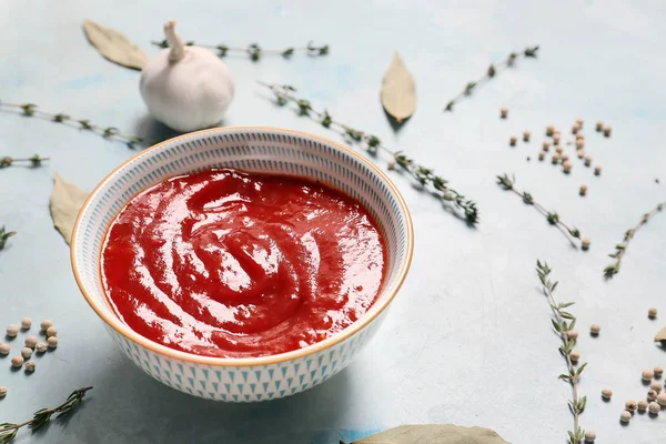 Bowl with tomato sauce and spices on color background — Stock Photo, Image