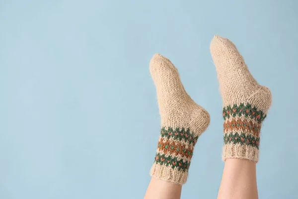 Benen van jonge vrouw in warme gebreide sokken op kleur achtergrond — Stockfoto