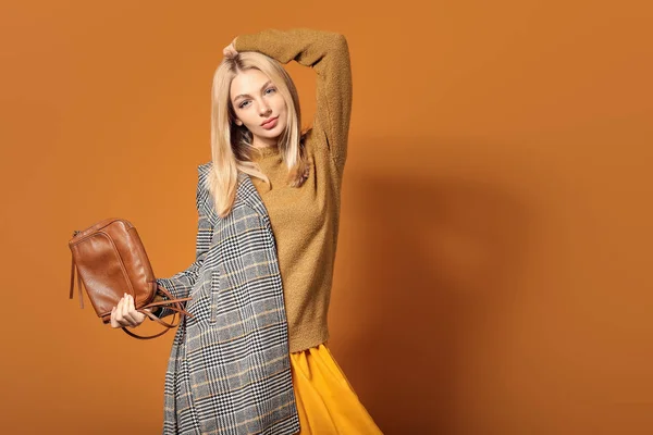 Jonge vrouw in warme trui en met stijlvolle tas op kleur achtergrond — Stockfoto