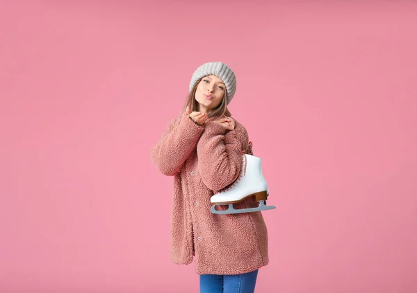 Belle jeune femme avec patins à glace soufflant baiser sur fond de couleur — Photo