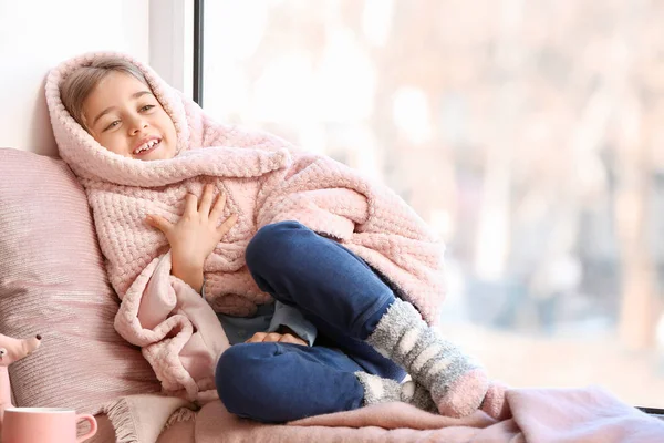 Cute little girl on window sill at home — Stock Photo, Image