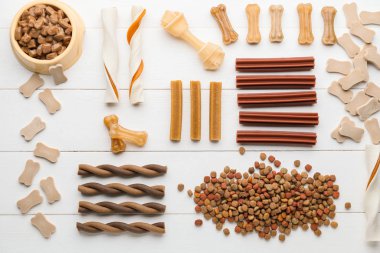 Beyaz ahşap arka planda farklı evcil hayvan yemekleri.