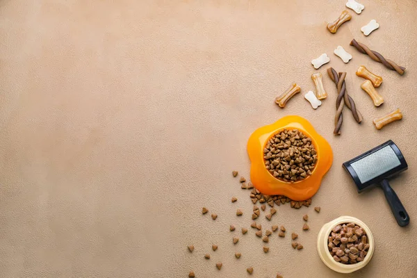 Bowls with pet food and brush on color background — Stock Photo, Image