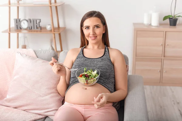 Hermosa mujer embarazada con ensalada saludable en casa — Foto de Stock