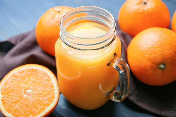 Mason jar of fresh orange juice and fruit on table — Stock Photo, Image