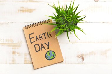 Dünya Günü yazılı defter ve hafif ahşap arkaplan üzerine bitki