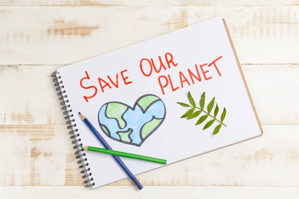 Notebook with drawing and text SAVE OUR PLANET on wooden background. Earth Day celebration — Stock Photo, Image