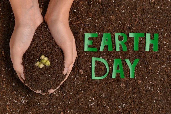Female hands with soil and text EARTH DAY — Stock Photo, Image