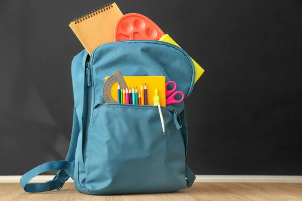 Mochila escolar con papelería en la mesa en el aula — Foto de Stock