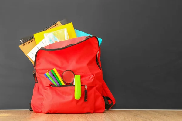 School backpack with stationery on table in classroom — Stock Photo, Image