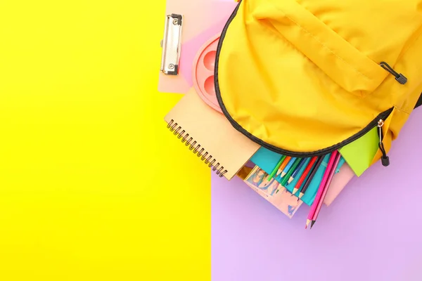 School backpack with stationery on color background — Stock Photo, Image