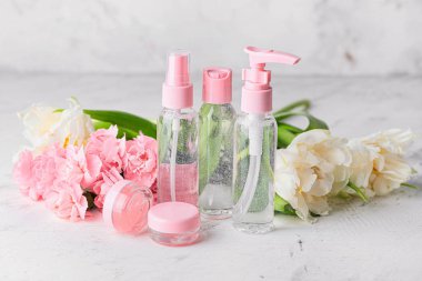 Beyaz arka planda çiçekli farklı kozmetik ürünleri