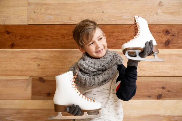 Cute little boy with ice skates against wooden background — Stock Photo, Image