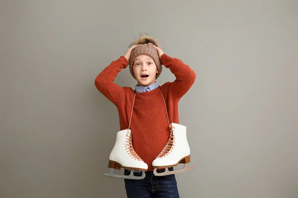 Surprised little boy with ice skates against grey background — Stockfoto
