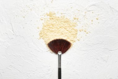 Makeup brush and cosmetics on light background