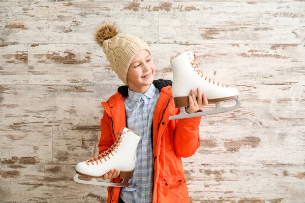 Cute little boy with ice skates against wooden background — Stock Photo, Image