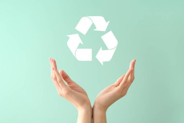 Female hands and symbol of recycling on color background