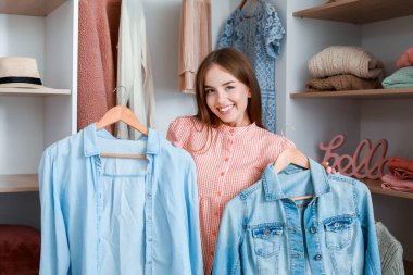 Güzel, genç bir kadın büyük gardıroptan kıyafet seçiyor.