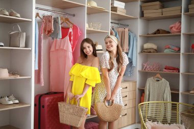 Beautiful young women choosing clothes from large wardrobe
