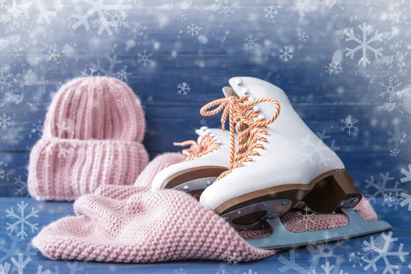 Pattini da ghiaccio, cappello caldo e sciarpa su sfondo di legno a colori — Foto Stock