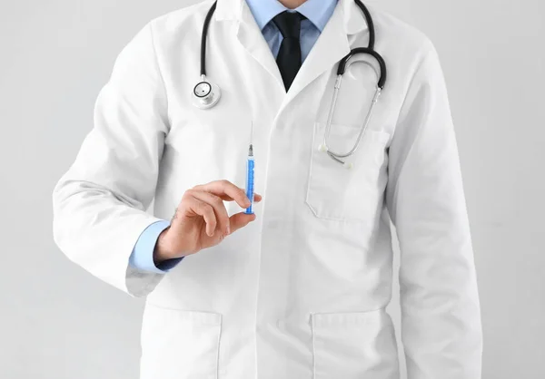 Doctor with syringe on light background, closeup — Stok fotoğraf