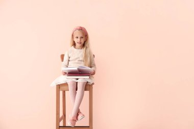 Little girl reading book on color background