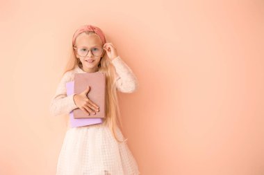 Little girl with books on color background