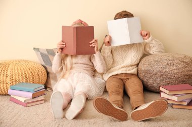 Renk duvarının yanında kitap okuyan küçük çocuklar.