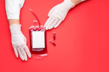 Hands of doctor with blood pack for transfusion and test tubes on color background