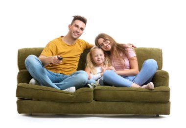 Happy young family watching TV while sitting on sofa against white background