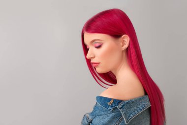 Açık arkaplanda sıradışı saç rengi olan güzel bir genç kadın.