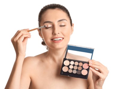 Güzel genç bir kadın beyaz arka plana makyaj yapıyor.