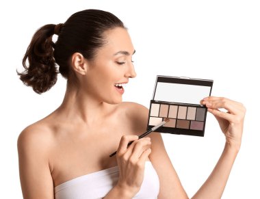 Güzel genç bir kadın beyaz arka plana makyaj yapıyor.