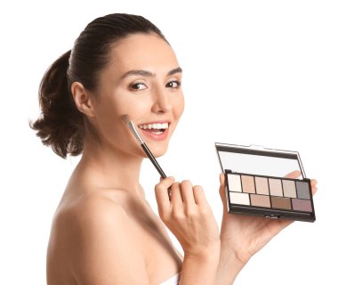 Güzel genç bir kadın beyaz arka plana makyaj yapıyor.