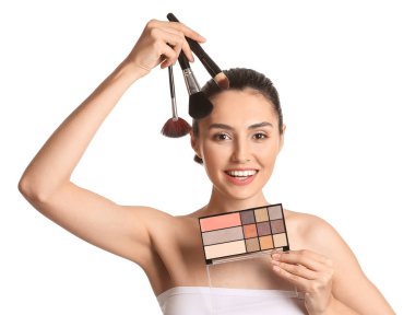 Güzel genç bir kadın beyaz arka plana makyaj yapıyor.