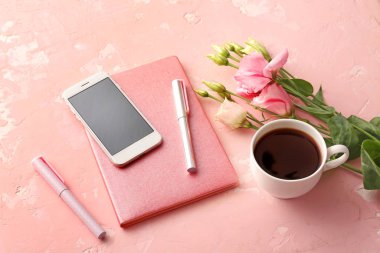 Cep telefonlu defter, kahve fincanı ve renkli kalemler.