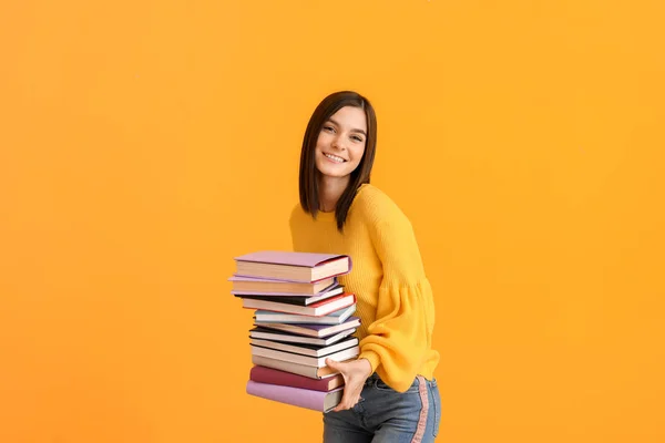 Hermosa mujer joven con muchos libros sobre fondo de color —  Fotos de Stock