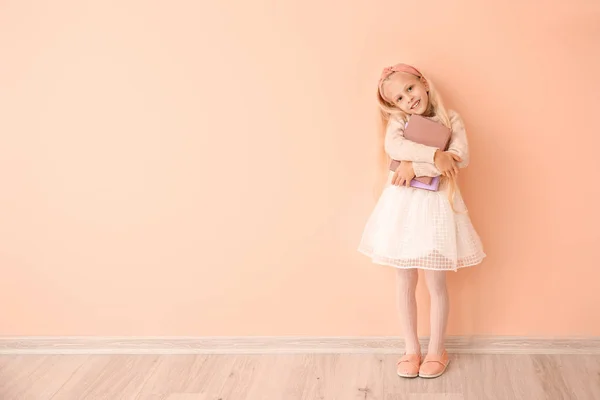 Kleines Mädchen mit Büchern in der Nähe der Farbwand — Stockfoto