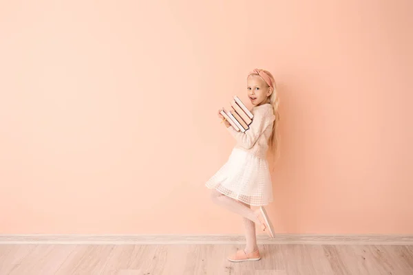 Niña con libros cerca de la pared de color — Foto de Stock