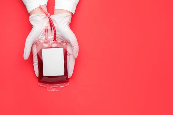 Mãos de médico com bolsa de sangue para transfusão em fundo colorido — Fotografia de Stock