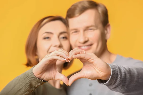 Hermosa pareja cogida de la mano en forma de corazón sobre fondo de color, primer plano —  Fotos de Stock
