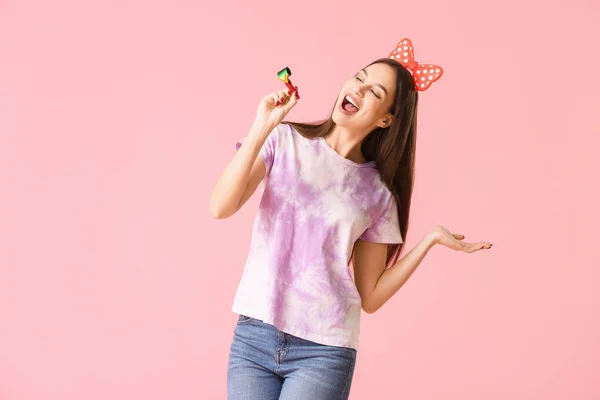 Vrouw met feestfluitje op kleur achtergrond. 1 april dwaze dag viering — Stockfoto