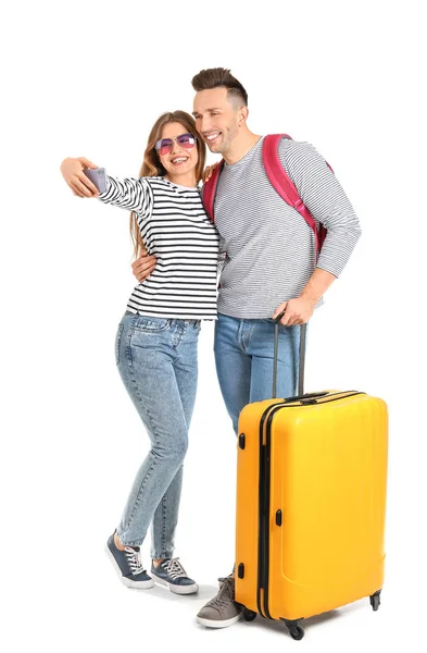 Couple of tourists with luggage taking selfie on white background — 图库照片