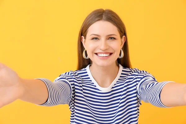 Beautiful young woman taking selfie on color background — Stock Photo, Image