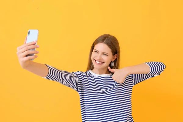 Schöne junge Frau macht Selfie auf farbigem Hintergrund — Stockfoto