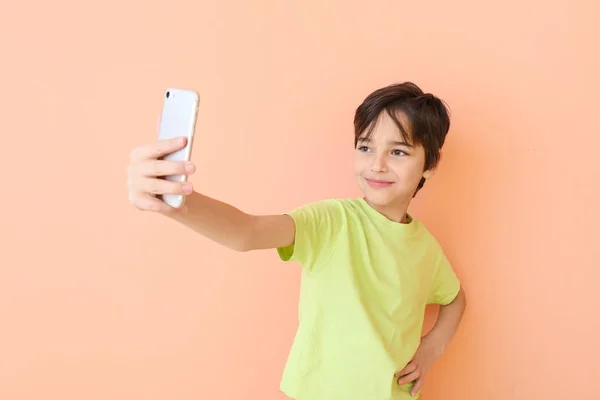 Cute little boy taking selfie on color background — Stock Photo, Image