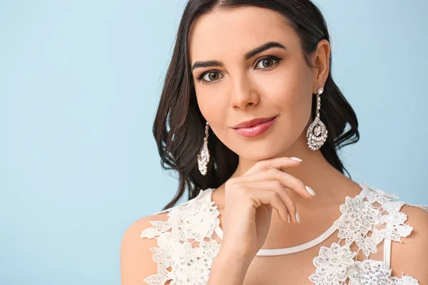 Young bride with beautiful jewelry on color background — Stock Photo, Image