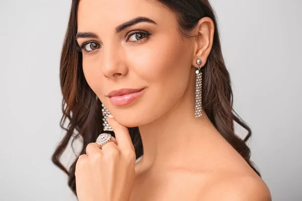 Jonge vrouw met mooie sieraden op lichte achtergrond — Stockfoto